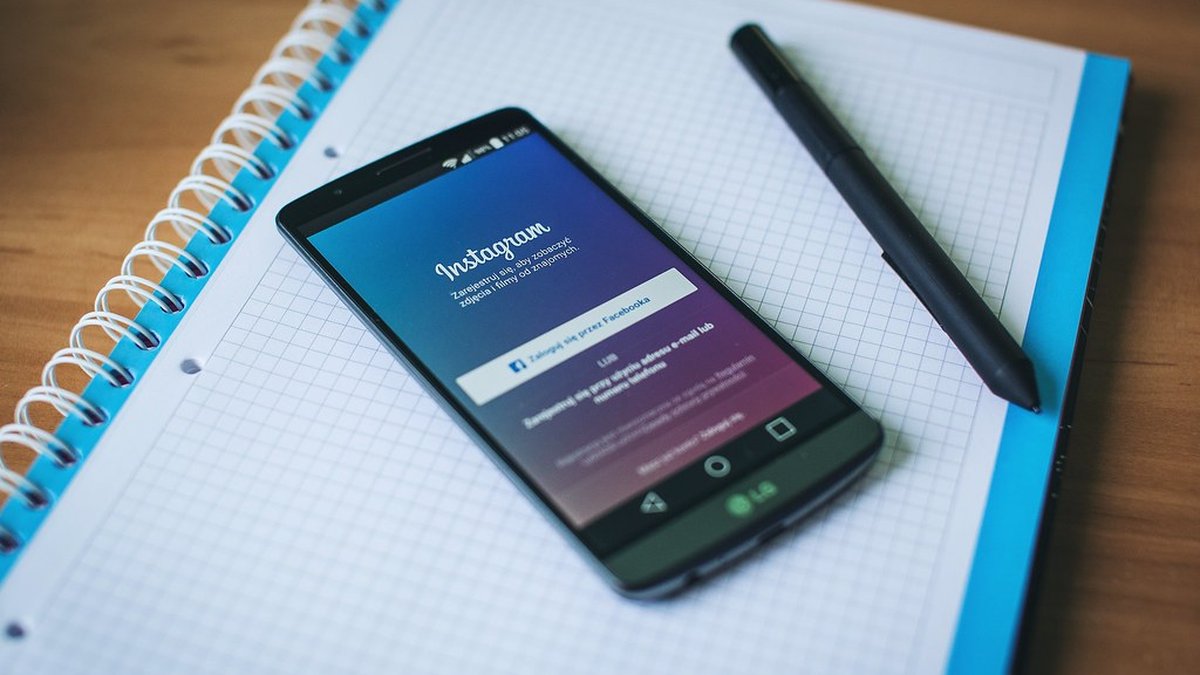 Smartphone con Instagram aperto su una scrivania, gestione social in estate